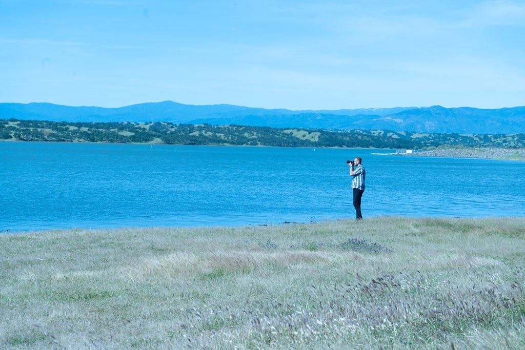 Kyle photographing a lakeside landscape with rolling hills